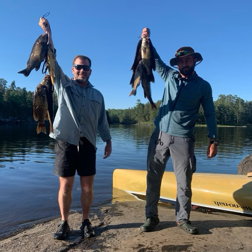 two men holding bunch of fish