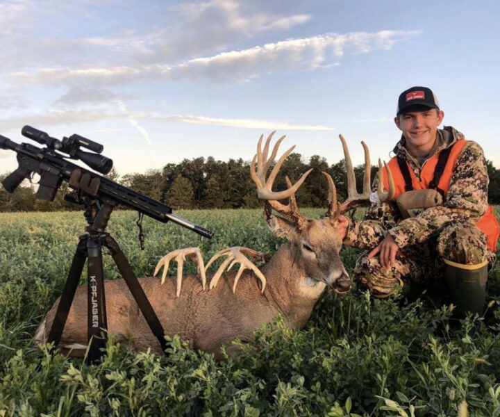 young hunter with rifle and dead deer